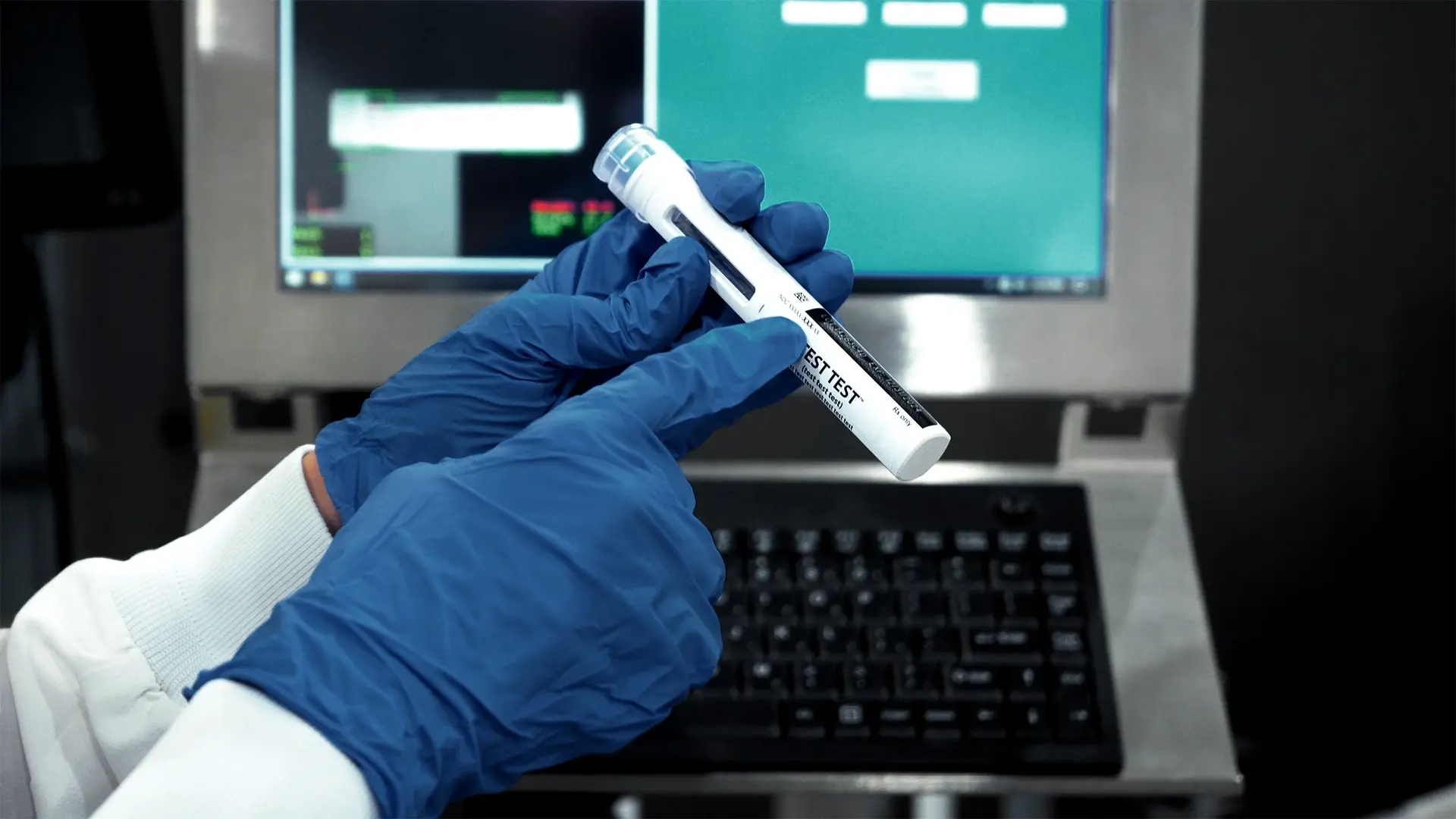 Gloved hands holding and inspecting a medical device component in a controlled lab environment, with digital screens in the background, representing device testing and quality control. Visual supports PCI Pharma Services’ participation in the PDA Miniverse Medical Devices, Combination Products and Connected Health Conference 2026.