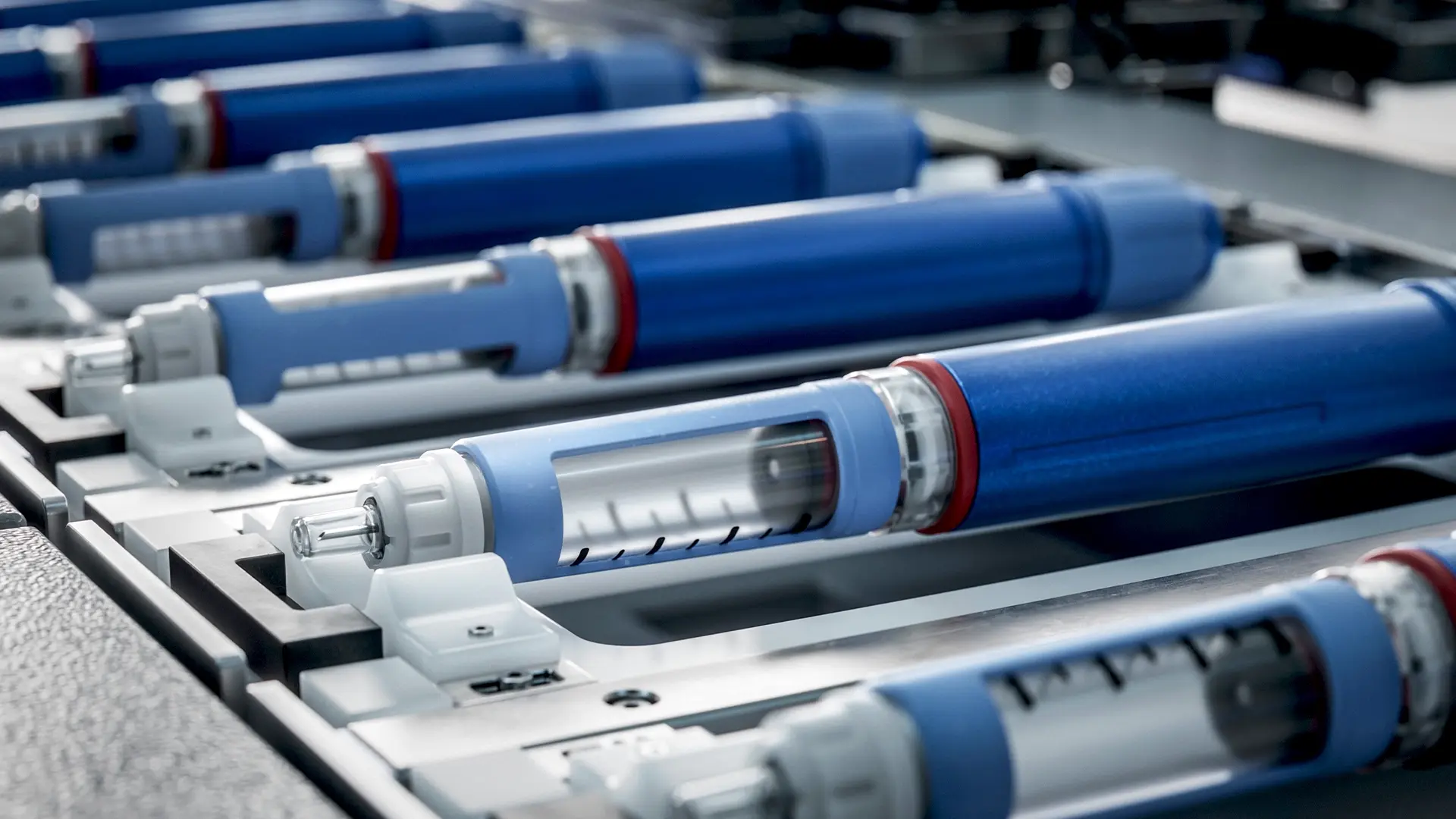 Prefilled syringes aligned on a pharmaceutical production line, highlighting drug-device combination manufacturing and precision dosing for clinical trials