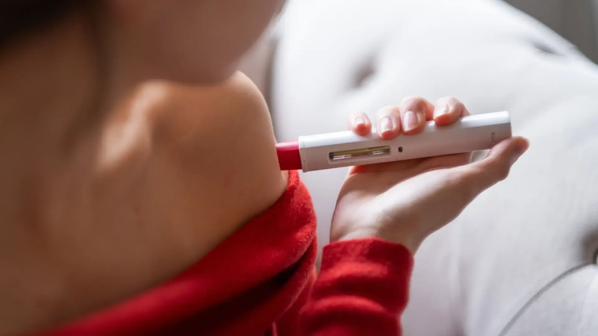 Person using a self-injection device for at-home administration of a drug-device combination therapy, highlighting patient-centric injectable treatment and combination product usability