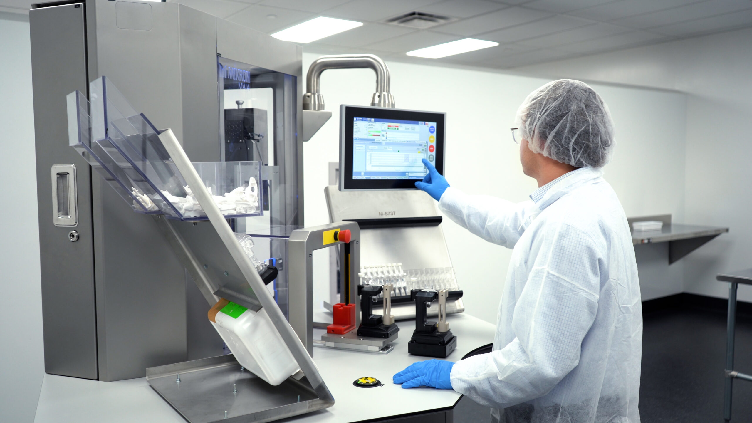 Scientist in sterile gown operating automated packaging equipment, representing PCI Pharma’s advanced technology in clinical supply management.